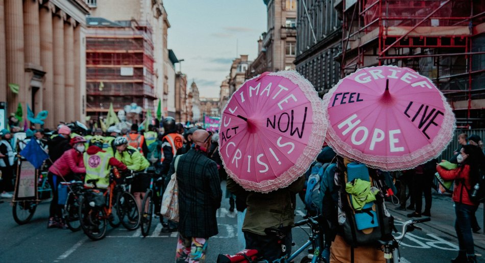 En gruppe mennesker som går ned en gate med rosa paraplyer på en klimaprotest.